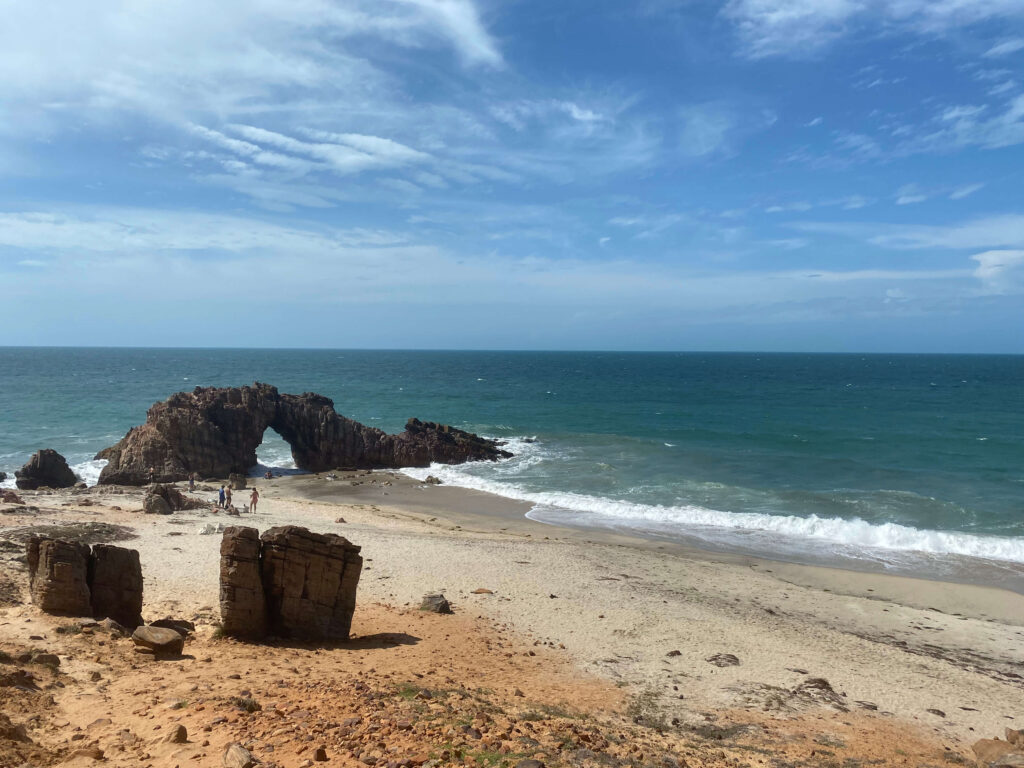 Pedra furada e praia ao fundo em Jericoacoara